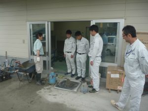 富山菱光コンクリート工業さんの試験室前でコンクリートの試験について説明を受ける３名の新入社員です。